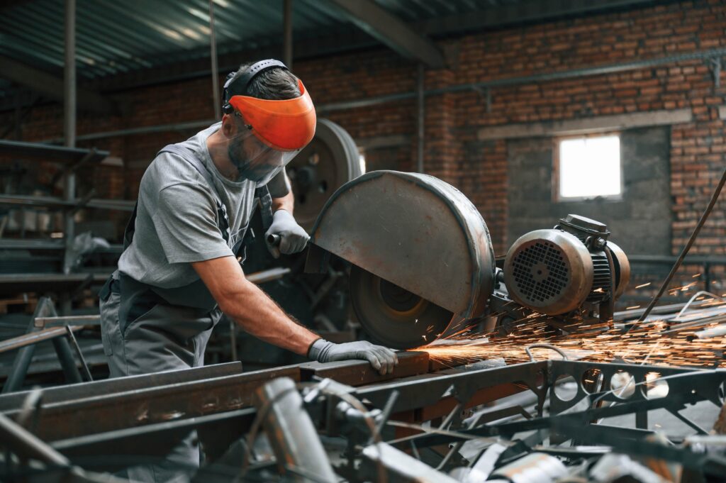 Metalworker cutting steel, demonstrating PPE training requirements Canada with protective equipment for workplace safety compliance.