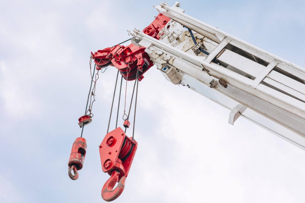 Boom truck safety tips in action: Operator uses proper lifting techniques and PPE while hoisting beams during construction.