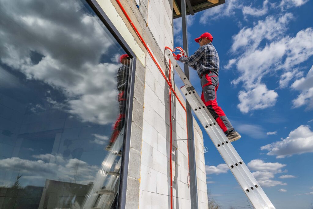 Construction worker with hard hat prepares to climb ladder safely, demonstrating ladder safety guidelines in action.