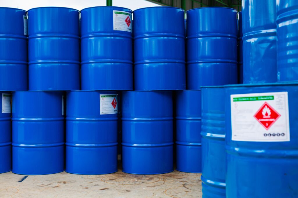 Blue chemical barrels with hazardous material labels, showing common TDG compliance mistakes in packaging and labeling.