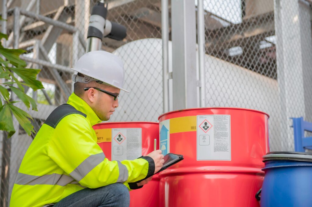 Worker inspecting hazardous materials drum, emphasizing proper training and documentation to avoid TDG compliance mistakes.