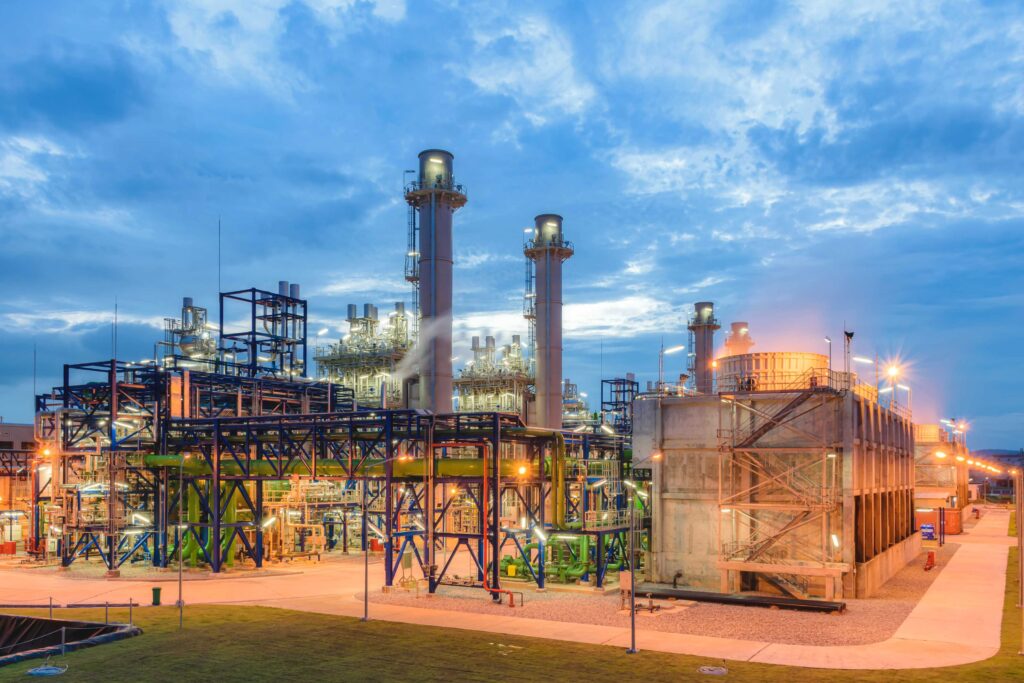  Large industrial plant with pipelines and gas processing equipment during evening lighting.