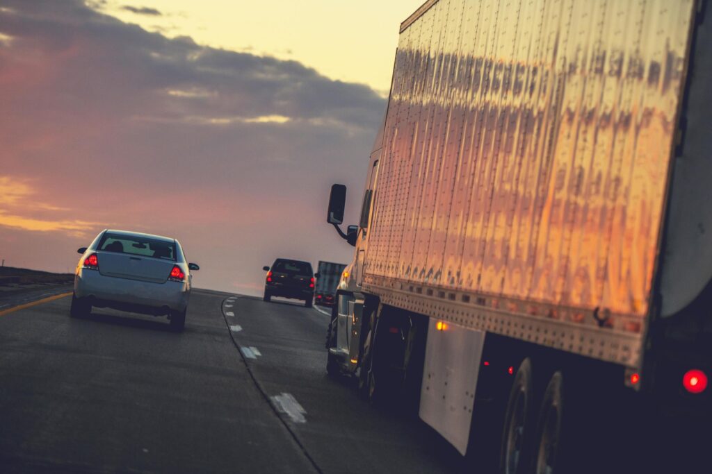  Transport trucks on a highway during sunset, emphasizing long-haul driving and the importance of managing hours-of-service limits.