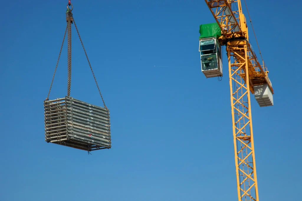 Crane lifting a heavy load with rigging cables during construction.