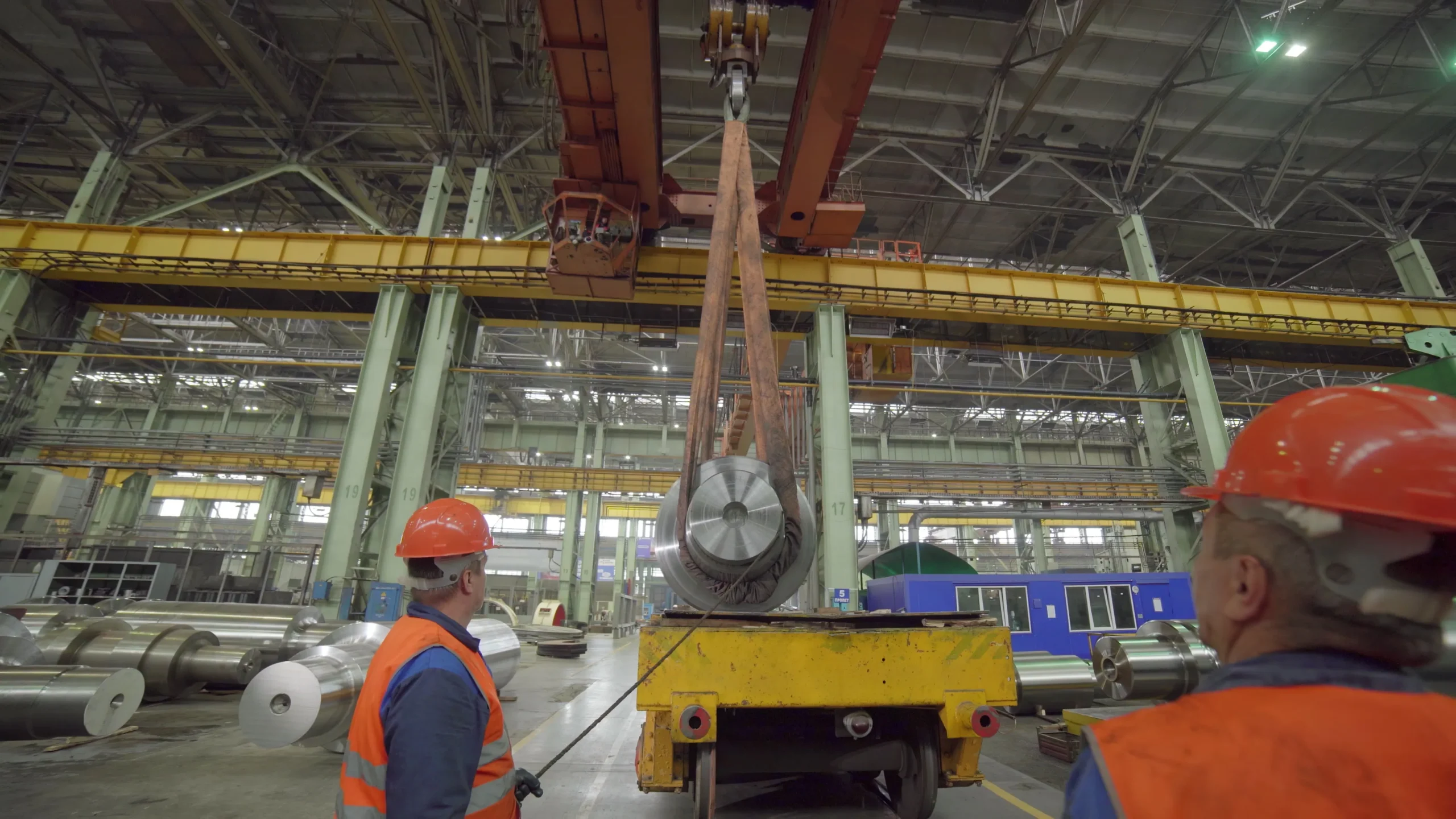 Two riggers guiding a suspended load with tag lines, emphasizing teamwork and safe load control during lifting operations.